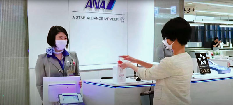 Aviation analytics helps make ANA successful. Woman using sanitizer at an ANA gate. About to board.